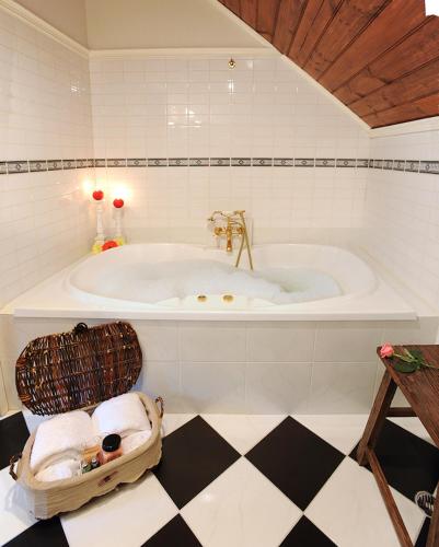 a bathroom with a large tub with a basket on the floor at Mary Cards Coach House in Olinda
