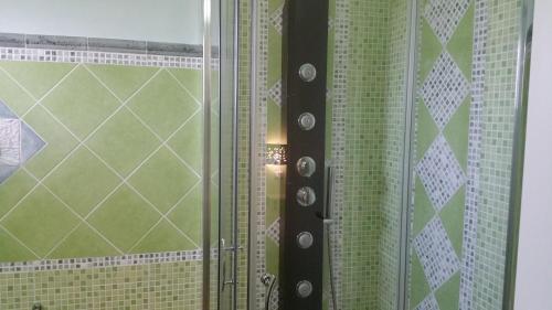 a bathroom with a shower with green and white tiles at Sa Branda Costa Country Alghero in Santa Maria la Palma