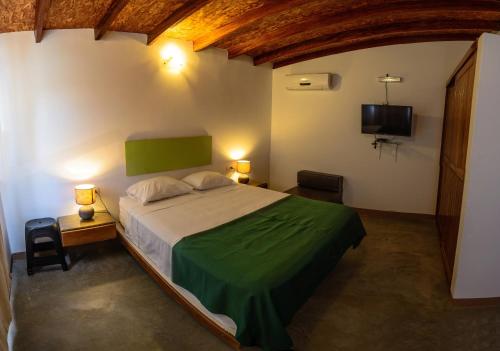 a bedroom with a bed and a tv and two lamps at Akas Hotel Apartamentos in Canoas De Punta Sal