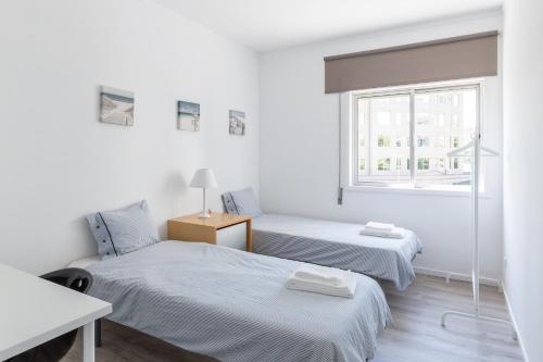 2 Betten in einem weißen Zimmer mit Fenster in der Unterkunft The Perfect Porto Apartment in Porto