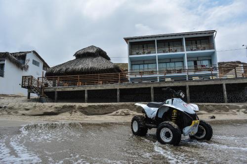 a four wheeler parked in the water in front of a building at Akas Hotel Apartamentos in Canoas De Punta Sal