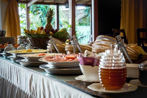 a buffet of food on a table with plates of food at Porto dos Casais Guest House Itacaré in Itacaré