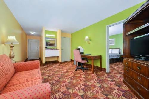 a hotel room with a couch and a desk at Super 8 by Wyndham Lake of the Ozarks in Eldon