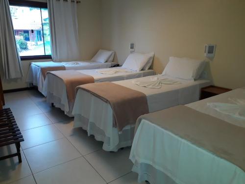 a group of three beds in a room at Costa Dourada Pousada in Arraial do Cabo