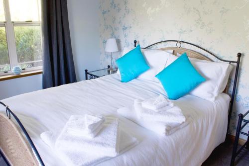 a white bed with blue pillows and towels on it at Bed & Breakfast at Tiffany's in McLaren Vale