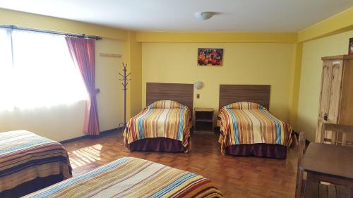 two beds in a room with yellow walls at Hotel Nuevo Sol in La Paz