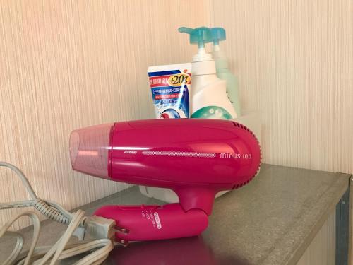 a pink blow dryer sitting on a counter with cleaning products at Guest House OkiniⅡ in Osaka