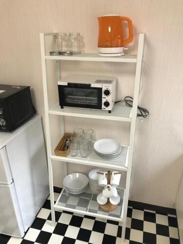 uma cozinha com uma prateleira branca com um micro-ondas e placas em Guest House OkiniⅡ em Osaka