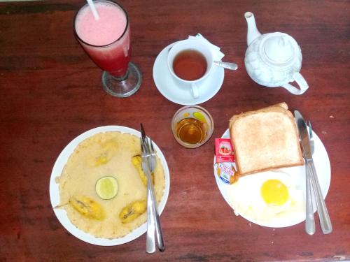 a table with a plate of eggs and toast and a drink at Villa Mangga Beach in Amed