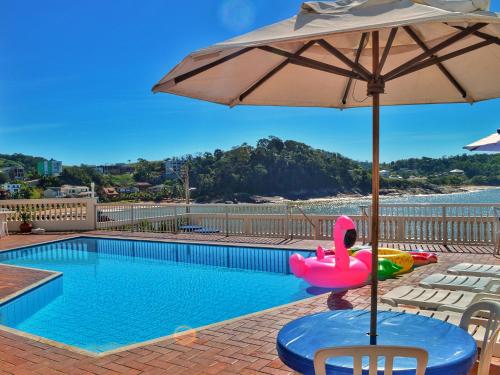 a pool with a pink swan and an umbrella at Hotel Portal da Lua in Iriri