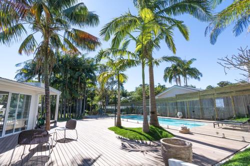 a patio with palm trees and a swimming pool at Byron Springs in Byron Bay