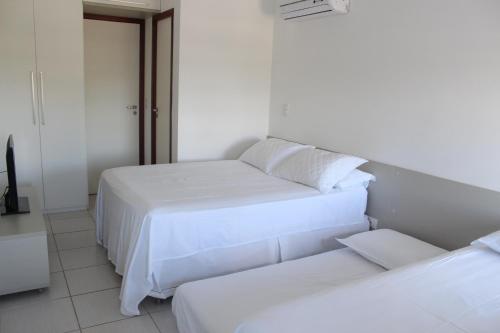 two beds in a room with white walls at Nannai Flat Duplex Muro Alto in Porto De Galinhas