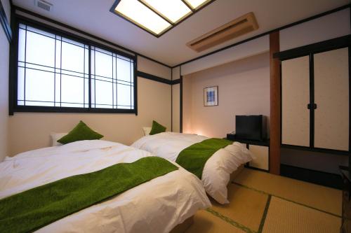 a room with two beds and a tv and windows at Yunosato Hayama in Beppu