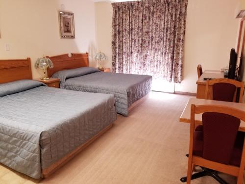 a hotel room with two beds and a television at New Imperial Inn in Cold Lake