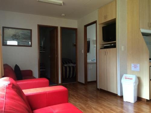 a living room with a red couch and a television at Smugglers Cove Holiday Village in Forster