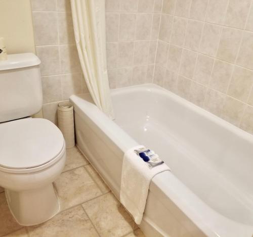 a bathroom with a toilet and a white bath tub at New Imperial Inn in Cold Lake
