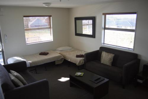 a living room with two beds and a couch at Pegasus Gateway Motels & Apartments in Rangiora
