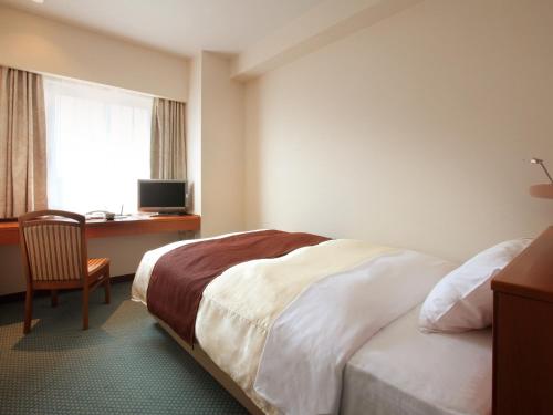 1 dormitorio con 1 cama y escritorio con ordenador en Hotel Pearl City Morioka, en Morioka