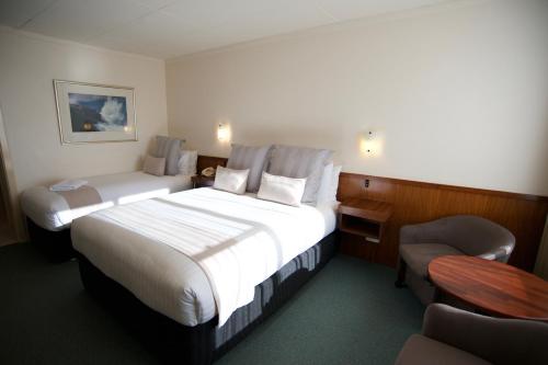 a hotel room with two beds and a chair at SureStay Hotel by Best Western The Clarence on Melville in Albany