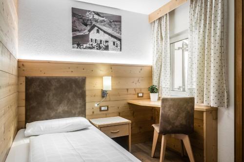 コルフォスコにあるPensione Vittoriaのベッドとデスクが備わるホテルルームです。