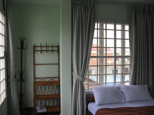 a bedroom with a bed and a large window at KOL House in Phnom Penh