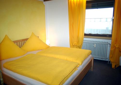 ヴァルメンシュタイナハにあるFerienwohnung Haus am Dürrberg "St. Georg"のベッドルーム1室(黄色いシーツ付きのベッド1台、窓付)