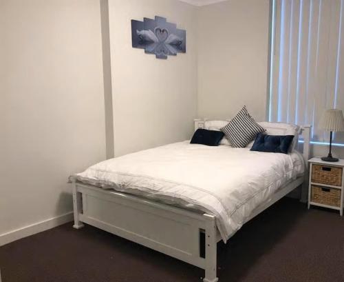 a white bed in a bedroom with a flower picture on the wall at Shine Apartment in Liverpool