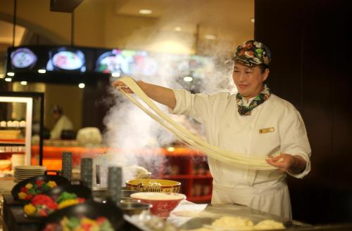 a chef standing in a kitchen preparing food at Shangri-La Harbin in Harbin