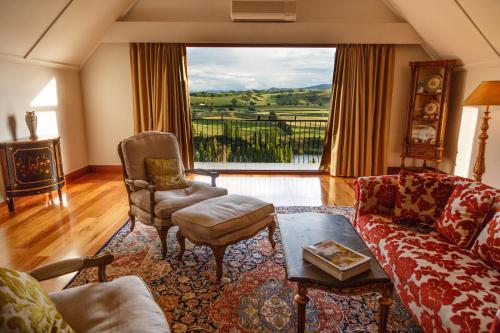 a living room with a couch and chairs and a large window at Lake Karapiro Lodge in Tirau