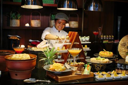 um chef que prepara comida num buffet num restaurante em Anantara Riverside Bangkok Resort em Banguecoque