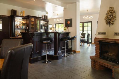 a bar with stools in a room with a fireplace at Drefahler Landgasthaus in Drefahl