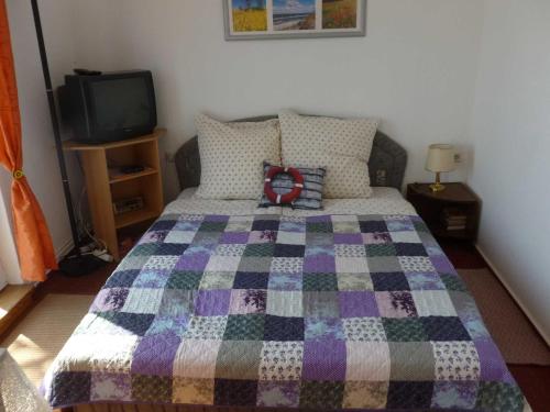 ein Schlafzimmer mit einem Bett mit einer Decke darauf in der Unterkunft Ahoi-Marie in Alt Reddevitz