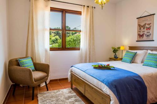 um quarto com uma cama, uma cadeira e uma janela em Casa Hedera em Breña Baja