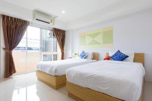 a hotel room with two beds and a window at Jr Mansion On Nut Soi 25 in Bangkok