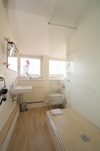 a white bathroom with a sink and a shower at Living am Carlsplatz Apartment in Düsseldorf