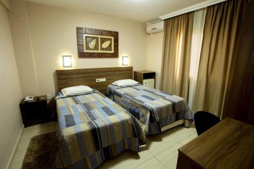 a hotel room with two beds and a table at Hotel do Comércio in Joaçaba