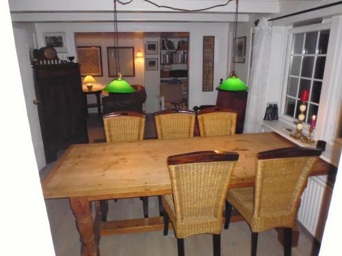 a dining room table and chairs with green lamps at Idyllic house near river and ocean in Leynar