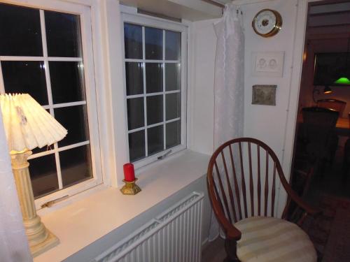 a chair sitting next to a window with a lamp at Idyllic house near river and ocean in Leynar