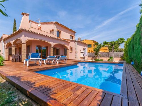 una piscina con terraza de madera y una casa en Belvilla by OYO Amfora 64 en Sant Pere Pescador