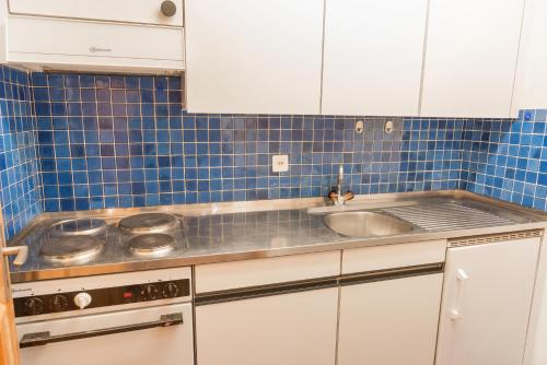 eine Küche mit einem Waschbecken und blauen Fliesen in der Unterkunft Chesa Tschierv - Celerina in Celerina