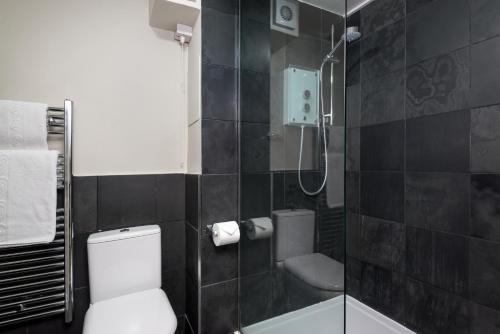 a bathroom with a white toilet and a shower at Balmoral Apartment in Keswick