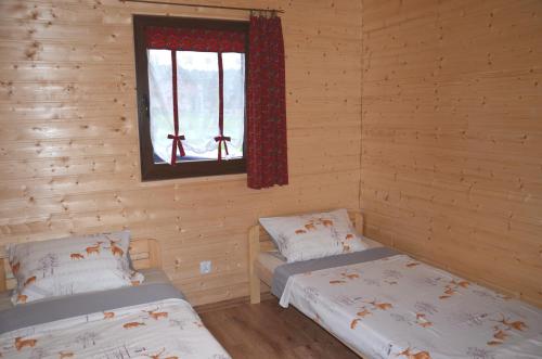 two beds in a log cabin with a window at Domki Złota Rybka nad Jeziorem- Jacuzzi in Zawóz