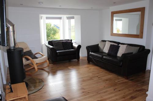 a living room with two black chairs and a mirror at 35 Newvalley in Stornoway