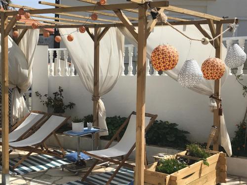 a patio with two chairs under a wooden pergola at MappaMundo in Ribamar