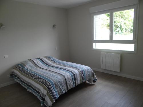 Bett in einem weißen Zimmer mit Fenster in der Unterkunft Labassere in Labassère
