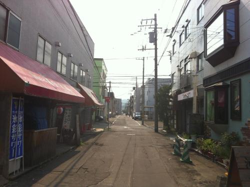 an empty street in an asian city with buildings at Guest House Yasube in Sapporo