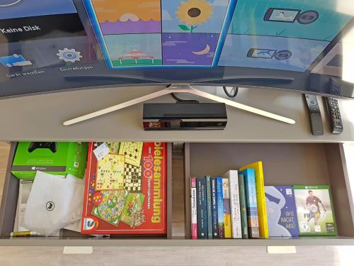 a book shelf with books and a monitor on top at Ostsee Perle 35 in Heiligenhafen
