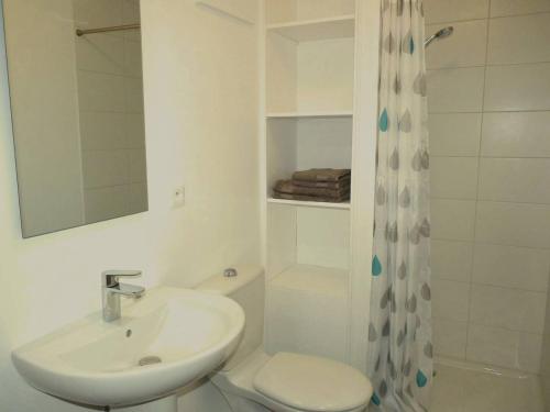 a white bathroom with a sink and a toilet at De l'Autre Côté in Garlin