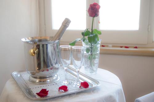 a table with a tray with glasses and a vase with roses at B&B Piccolo Hotel in Cortona
