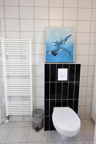 a bathroom with a toilet and a picture of dolphins at The Viking Country Club in Hjalteyri